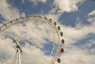 Low angle view of ferris wheel against cloudy sky