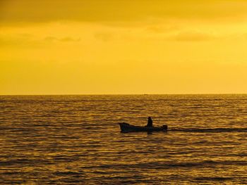 Silhouette boat in sea against orange sky