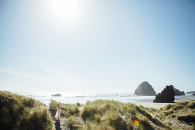 Rear view of young woman walking on trail leading towards beach