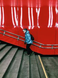 Side view of woman walking on staircase against wall