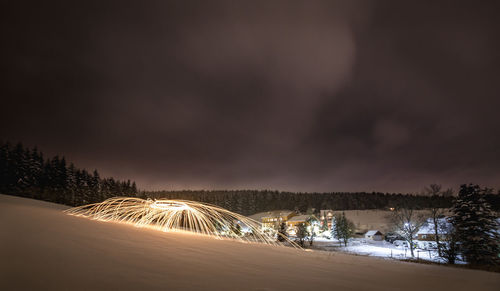 Illuminated trees against sky at night during winter