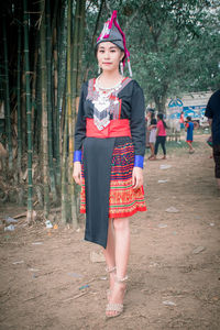 Portrait of smiling woman in traditional clothing standing against trees