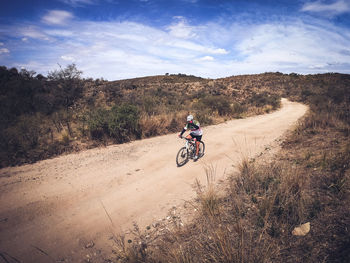 Man riding bicycle on road against sky