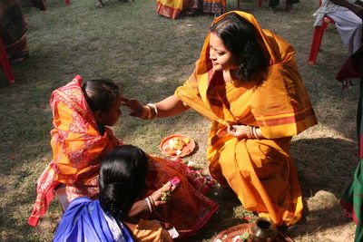 High angle view of woman applying tilak on girl outdoors