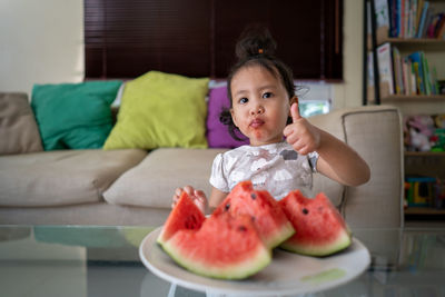 Portrait of cute girl sitting at home and eating watermelon 