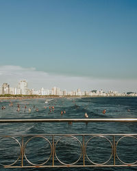 Cityscape by sea against clear sky