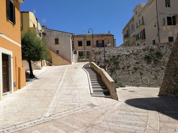 Footpath amidst buildings in city against sky