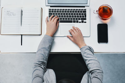 Midsection of woman using laptop on table