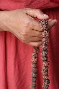 Midsection of woman holding prayer beads