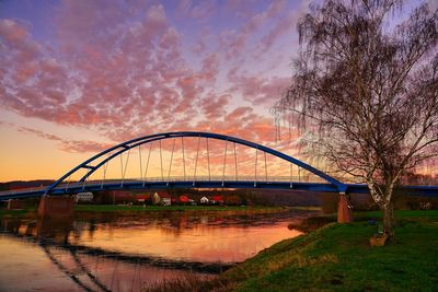 Arch bridge over river against sky during sunset