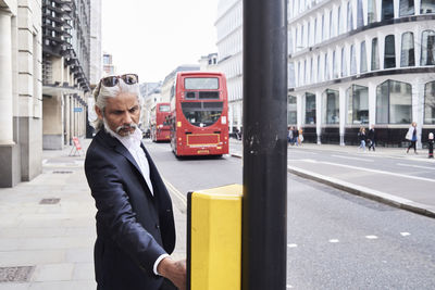 Uk, london, bearded senior businessman pressing traffic lights button