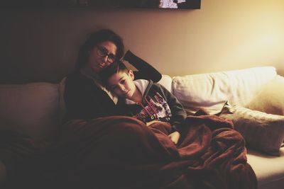 Young woman using mobile phone while relaxing on bed at home