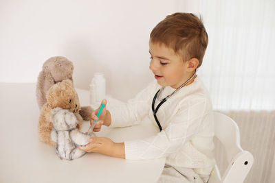 Cute little boy playing doctor at home and curing plush toy. sweet toddler child plays indoor. 