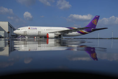 Airplane on airport runway against sky