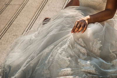 Midsection of bride wearing dress sitting on tiled floor