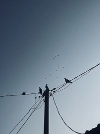 Low angle view of electricity pylon against clear sky