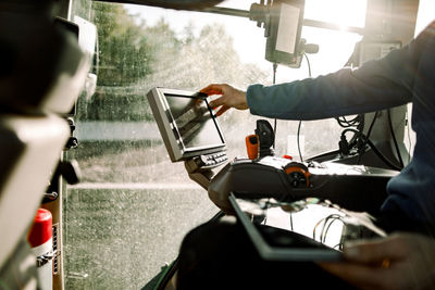 Hand of farmer operating computer sitting in tractor on sunny day