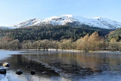 Scenic view of lake by mountains against sky