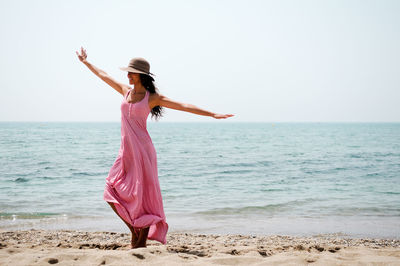 Woman with arms outstretched standing at beach