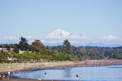 People enjoying at beach against blue sky