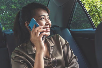 Young woman using mobile phone in car