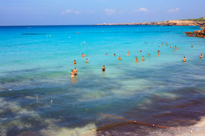 People swimming in sea against sky