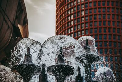 Low angle view of fountain against buildings in city