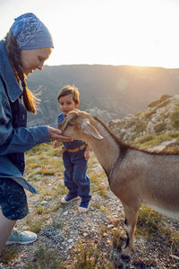 Boy a child of four years 4 and woman walks with goats on a mountain in dagestan during sunset