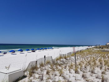 Scenic view of beach against clear blue sky