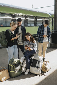 Family using smart phones while waiting for train at railroad station