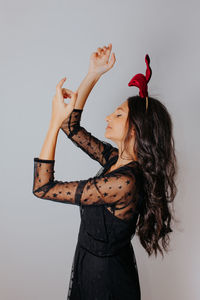 Young woman with arms raised standing against white background