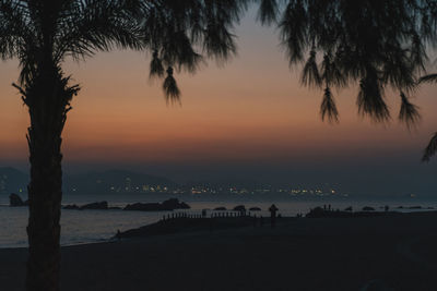 Silhouette palm trees on beach against sky at sunset