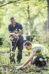 Instructor watching trainee planting at garden