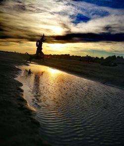 Silhouette people standing on beach against sky during sunset