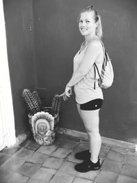 Portrait of a smiling young woman standing against wall