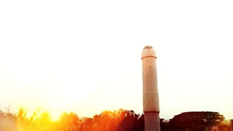 tower, architecture, built structure, lighthouse, low angle view, clear sky, guidance, building exterior, copy space, tall - high, sunset, direction, communications tower, sun, protection, no people, sunlight, outdoors, communication, safety