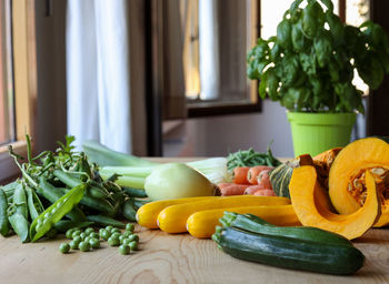 Green and orange vegetables on wooden table to prepare italian minestrone