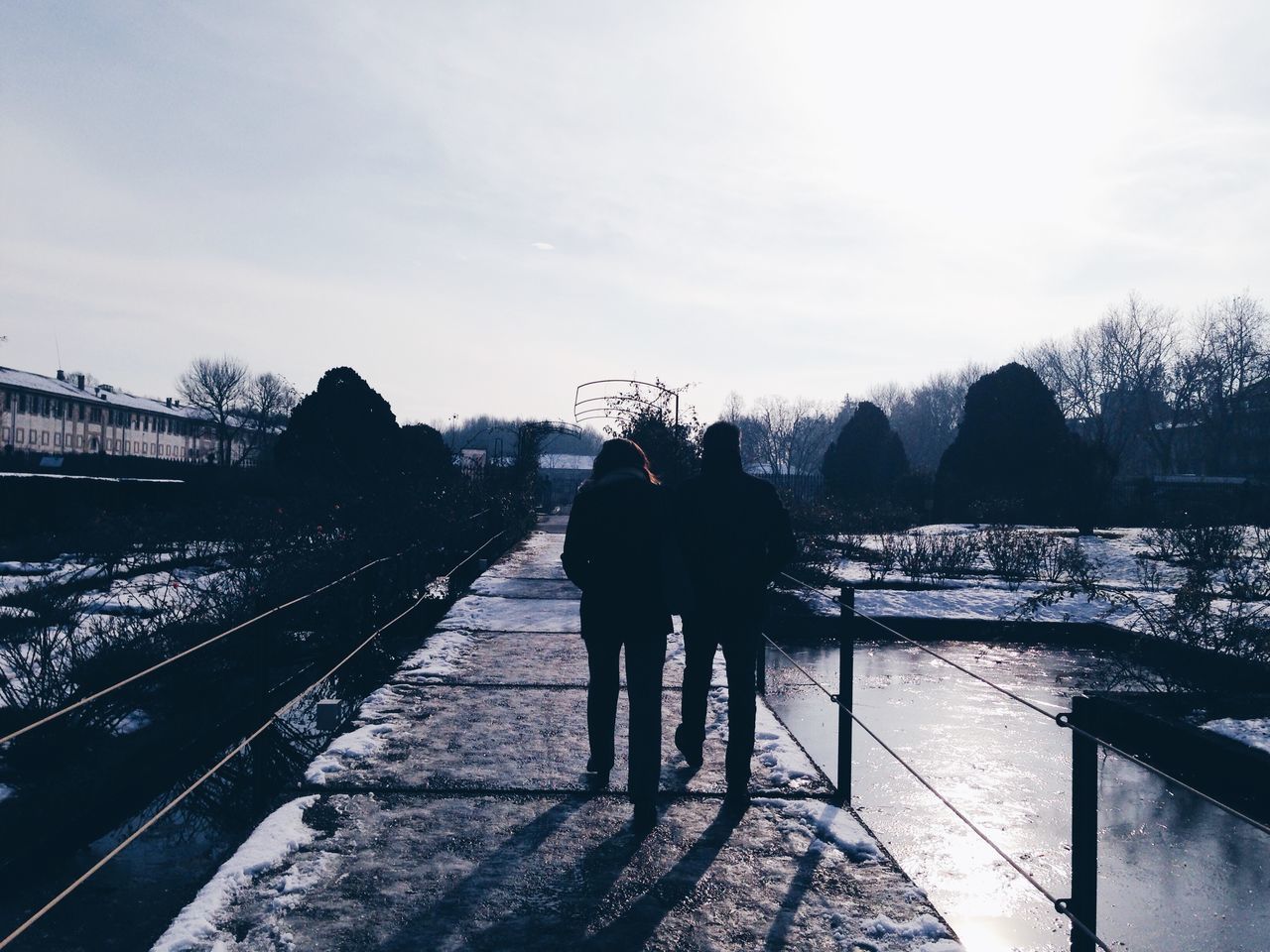 rear view, full length, sky, walking, lifestyles, men, person, leisure activity, railing, silhouette, standing, togetherness, cloud - sky, connection, shadow, bridge - man made structure, water