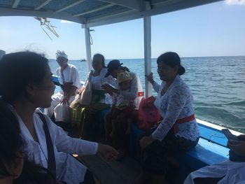 Rear view of people sitting by sea