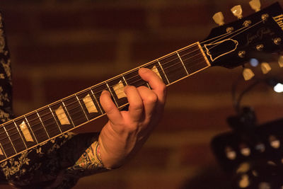 Cropped hand of man playing guitar on stage