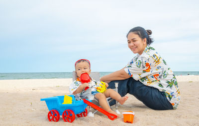 Happy boy with toy on beach against sky