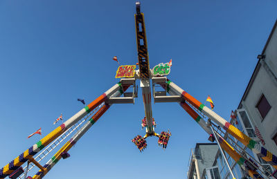 Colorful swinging amusement ride at park with thrill seekers against clear blue sky