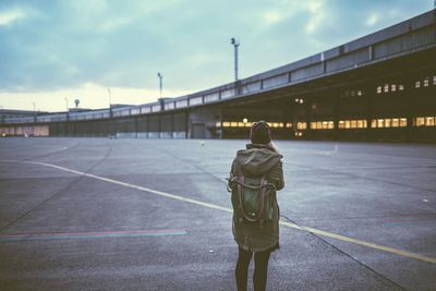 Rear view of woman standing in front of berlin tempelhof airport against sky