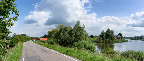 Panoramic view of road by trees against sky