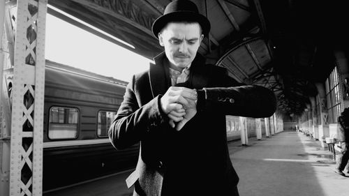 Young man checking time while standing at railroad station