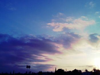 Low angle view of trees against cloudy sky