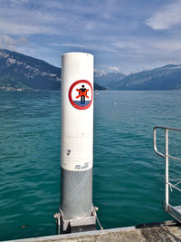 Information sign by sea against sky