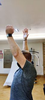 Midsection of man with arms raised at home