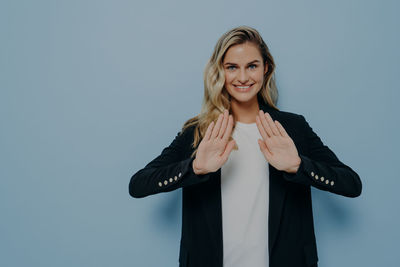 Portrait of young woman standing against blue background