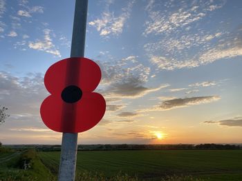 Red flag on field against sky during sunset